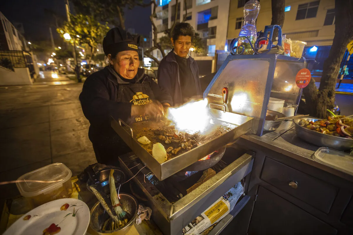 Lima street food stall serving anticuchos and picarones for backpackers.